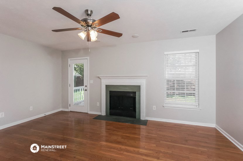 the living room of a home with a fireplace and a ceiling fan