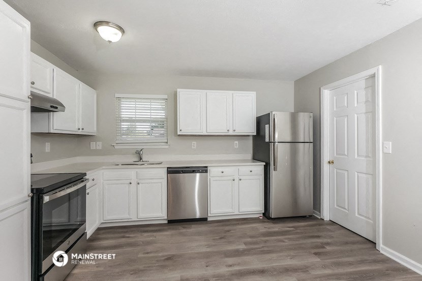 an empty kitchen with white cabinets and a stainless steel refrigerator