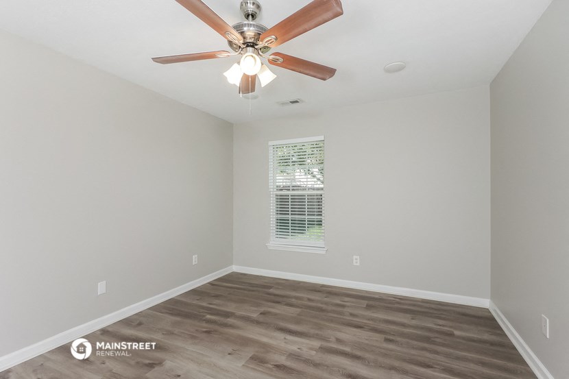 the spacious living room with ceiling fan and wood flooring