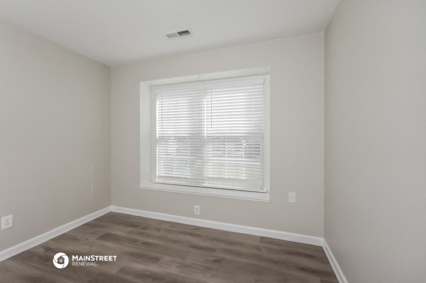 a bedroom with a large window and a wooden floor