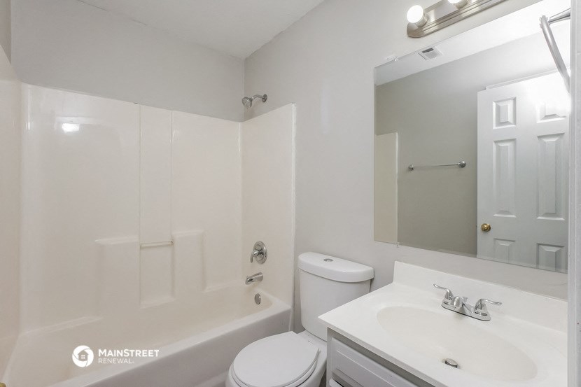 a white bathroom with a white sink and toilet and a tub