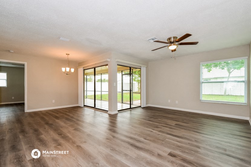 an empty living room with wood floors and a ceiling fan