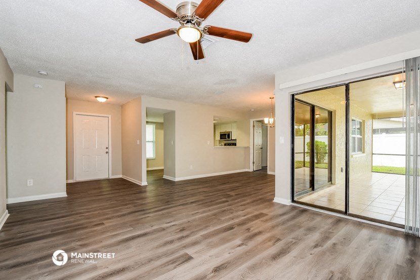 an empty living room with a ceiling fan and a mirror