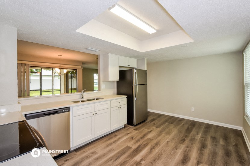 a kitchen with white cabinets and a stainless steel refrigerator