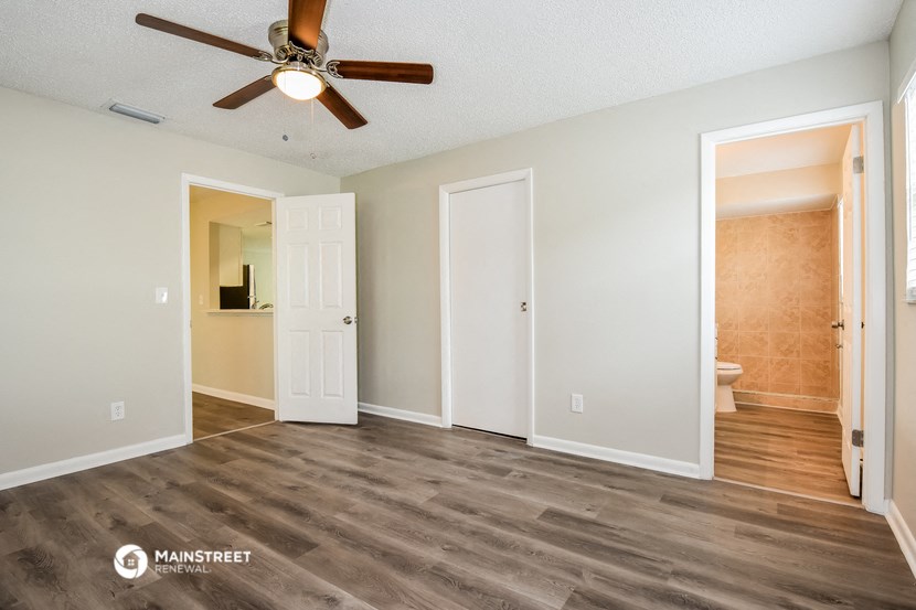 an empty living room with a ceiling fan and a bathroom