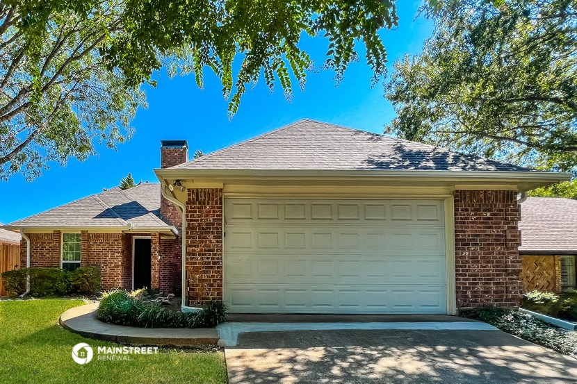 a white garage door in front of a brick house