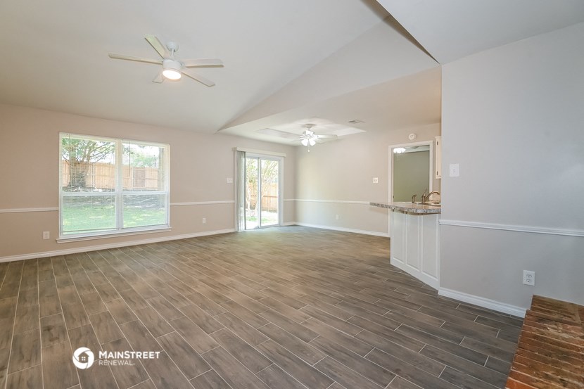 the living room of an empty house with a kitchen and a large window