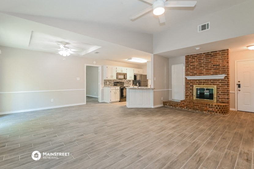 a living room with a fireplace and a kitchen