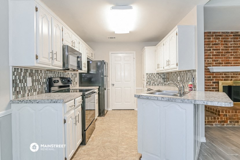 a kitchen with white cabinets and a brick wall