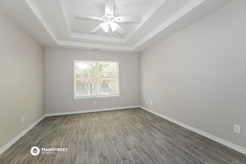 an empty room with a ceiling fan and a window