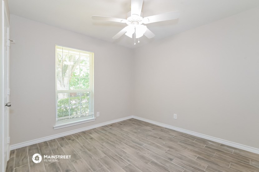 an empty room with a ceiling fan and a window