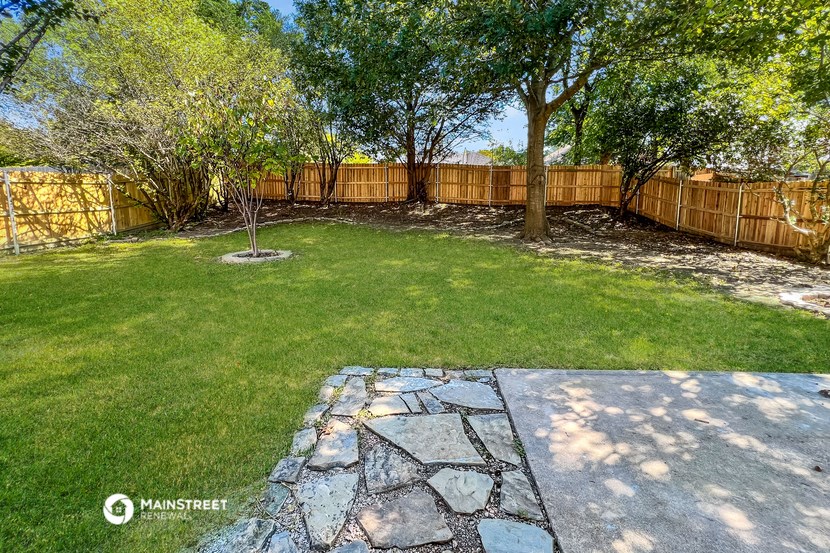 a backyard with a wooden fence and grass and trees