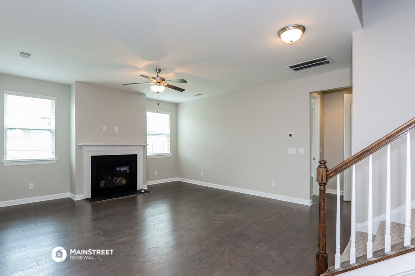 an empty living room with a fireplace and a ceiling fan