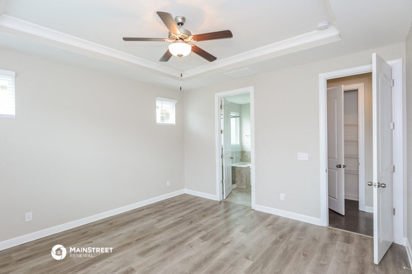 a living room with a ceiling fan and a door to a bathroom