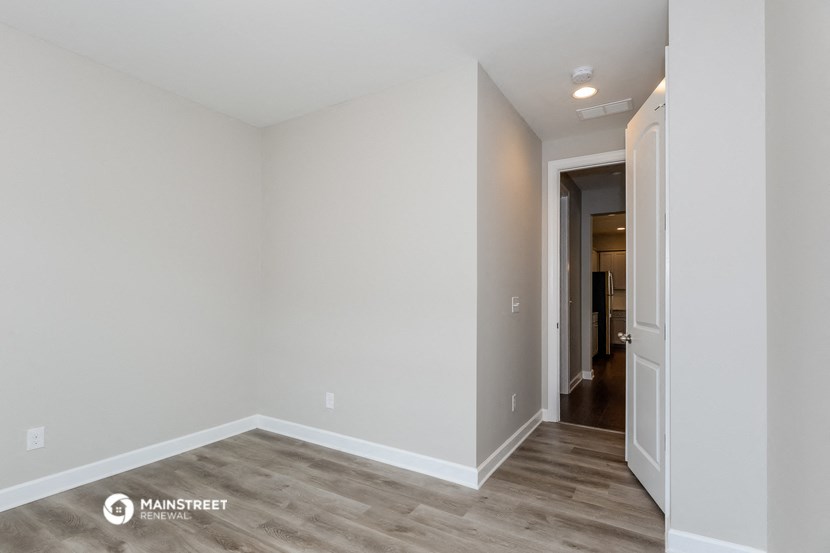 the living room and hallway of an apartment with white walls and wood flooring