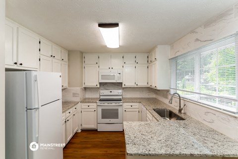 a kitchen with white cabinets and granite counter tops and white appliances