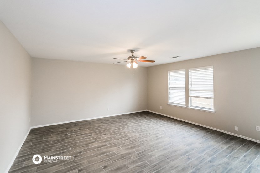 an empty living room with a ceiling fan and a window
