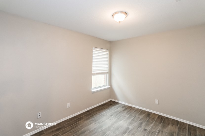 the spacious living room with wood flooring and a window