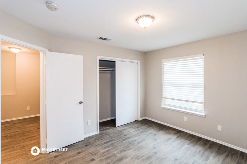 an empty living room with wood flooring and a door to a closet