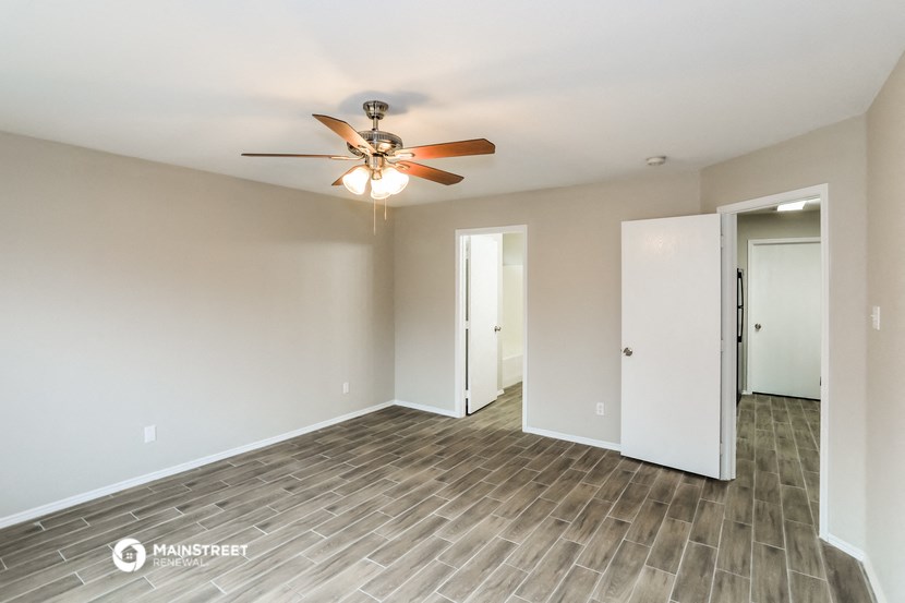 a empty living room with a ceiling fan and a closet