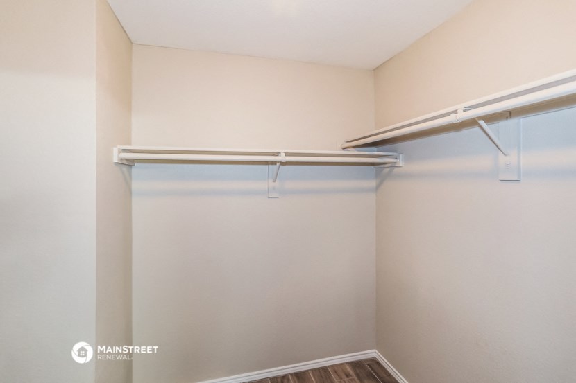 a spacious closet in a small white room with a hanging rail on the wall