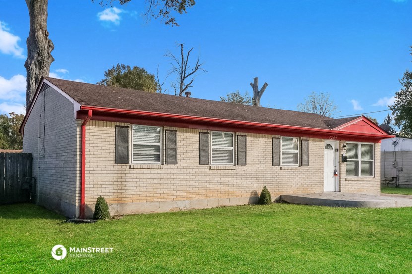an old brick house with a red roof and green grass