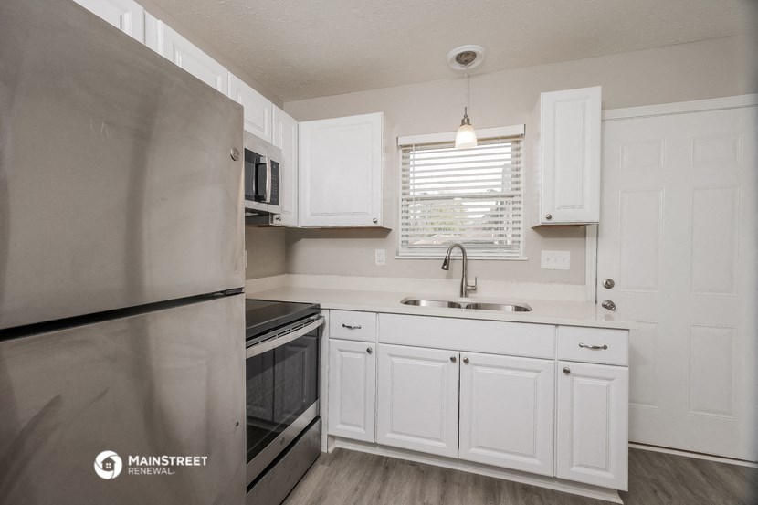 a kitchen with white cabinets and a stainless steel refrigerator