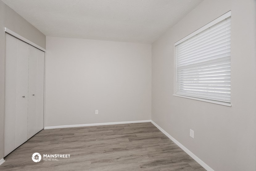 the bedroom of an apartment with a closet and a window