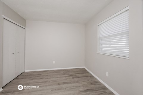 the bedroom of an apartment with a closet and a window