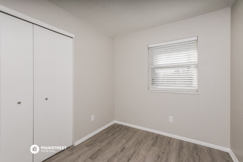 the bedroom of an apartment with white walls and wood floors