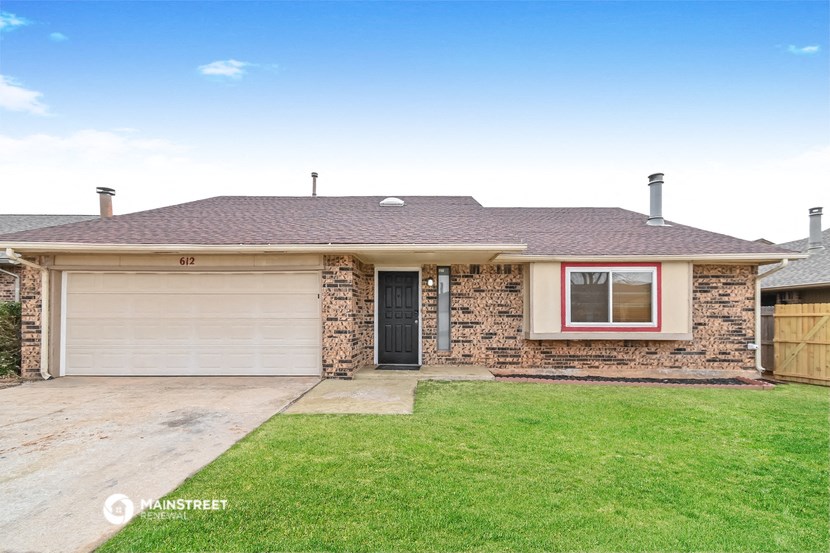 the front of a brick house with a yard and a garage door