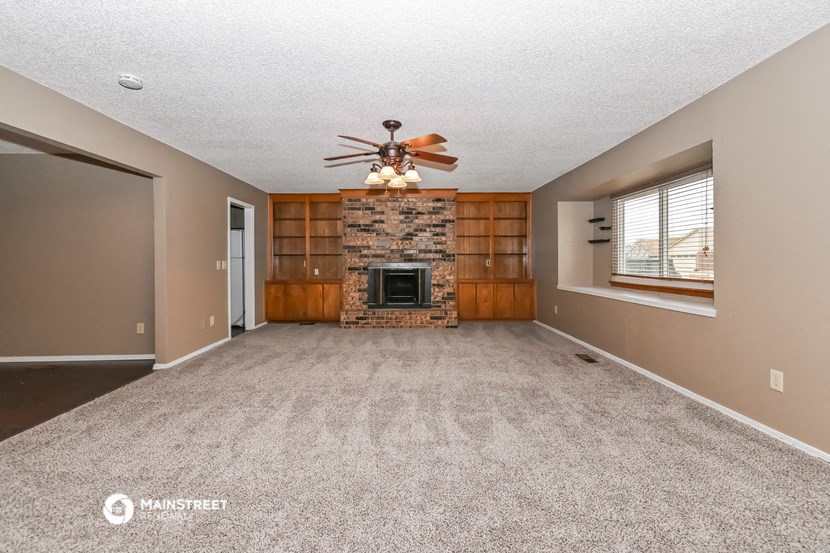 an empty living room with a fireplace and a ceiling fan