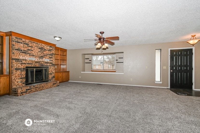 the living room has a fireplace and a ceiling fan