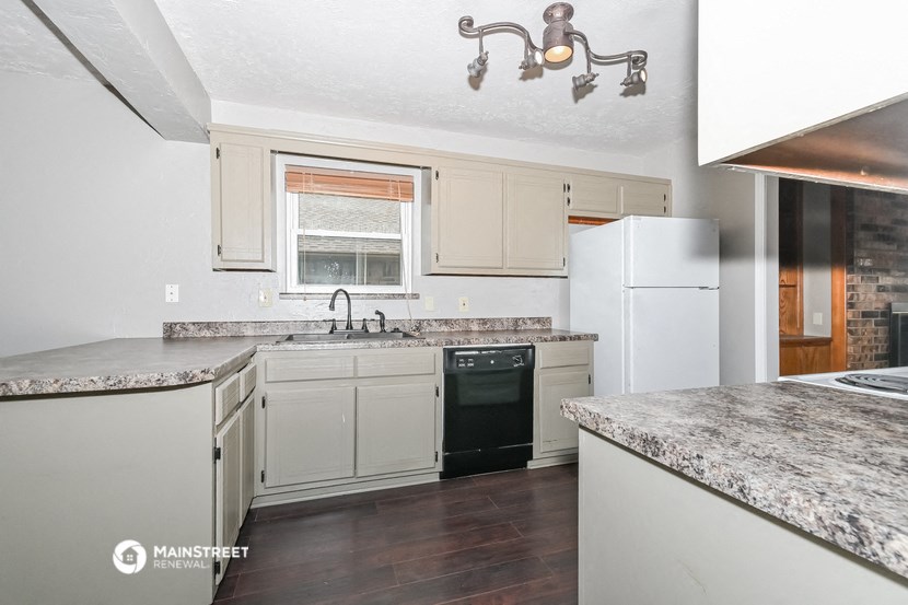 a kitchen with white cabinets and marble counter tops