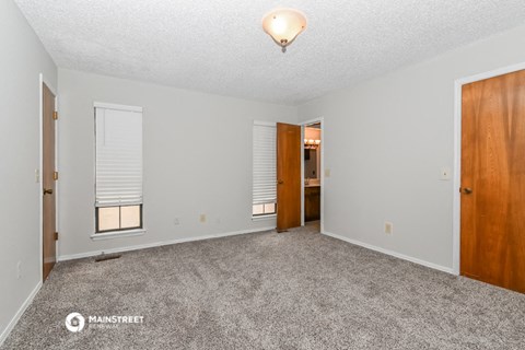 a spacious living room with carpet and a door to a bathroom