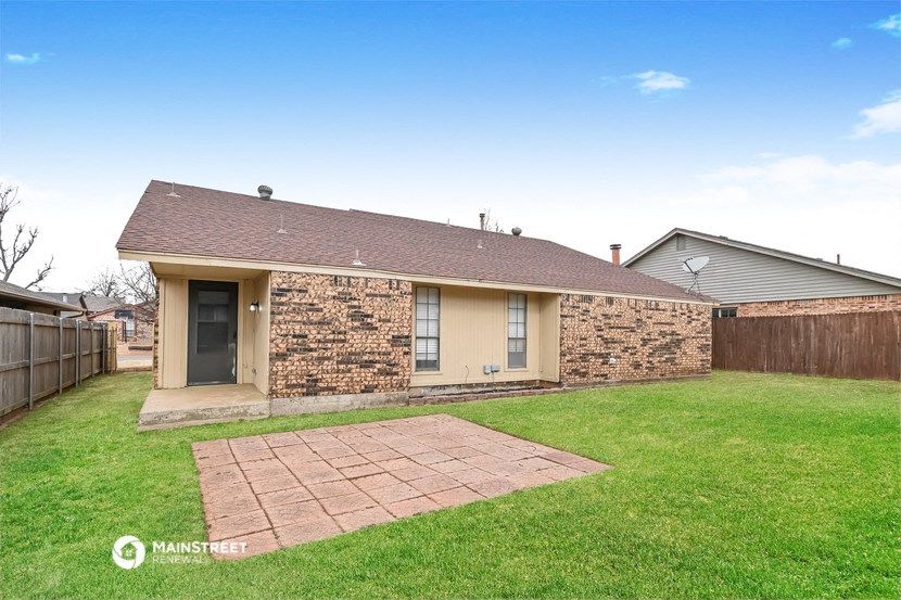 a small brick house with a lawn and a backyard