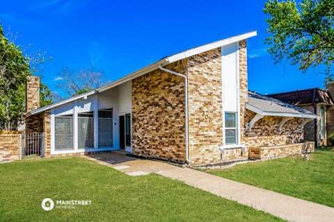 a small brick house with a lawn and a porch