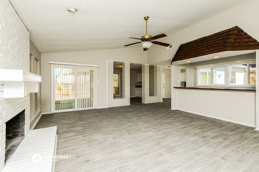 a large living room with a fireplace and a ceiling fan