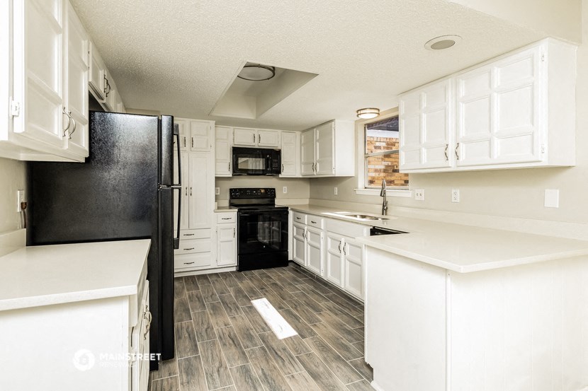 a kitchen with white cabinets and a black refrigerator