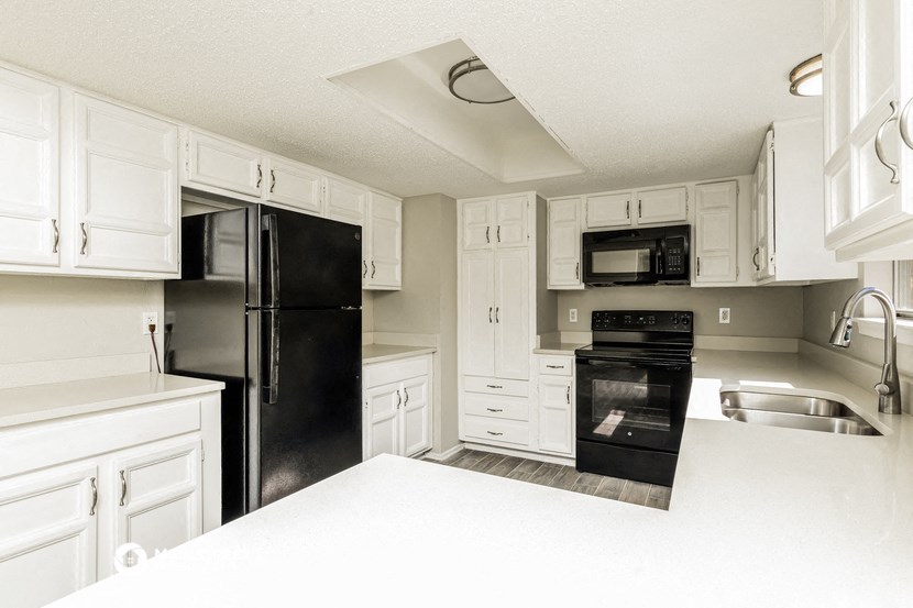 a kitchen with white cabinets and black appliances