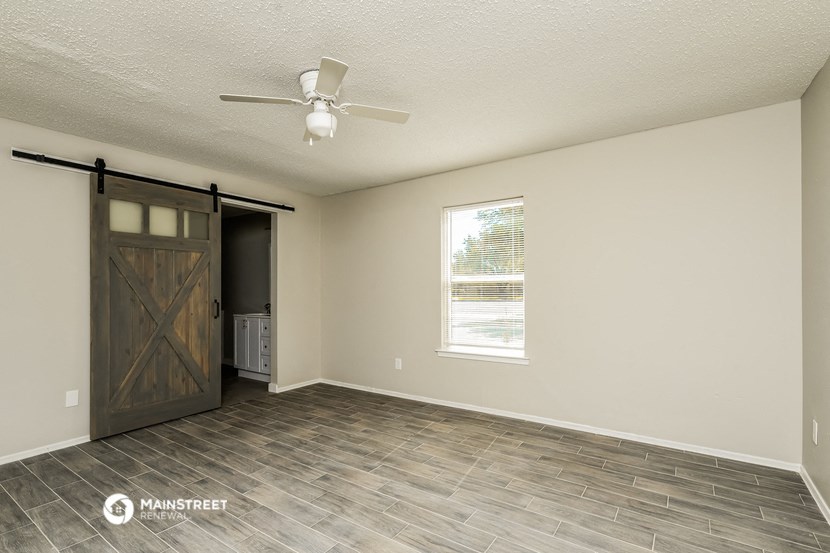 the living room with a barn door and a ceiling fan