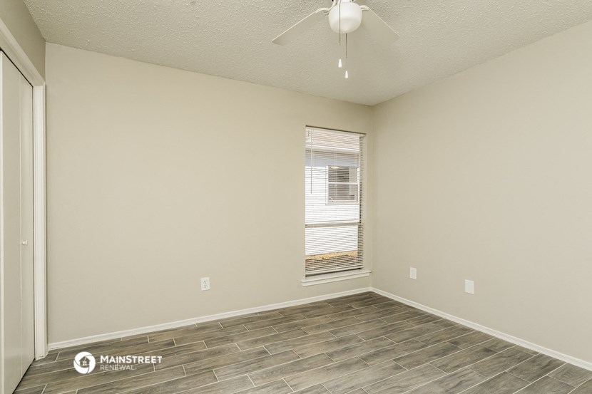 an empty living room with a window and a ceiling fan