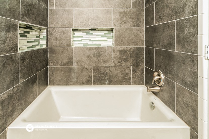 a white bath tub in a tiled bathroom