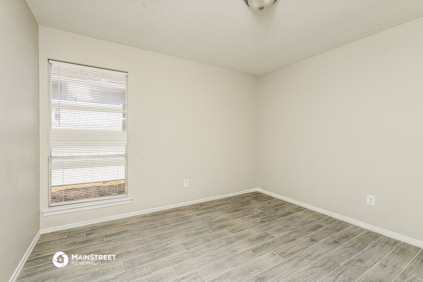 the spacious living room with wood flooring and a large window
