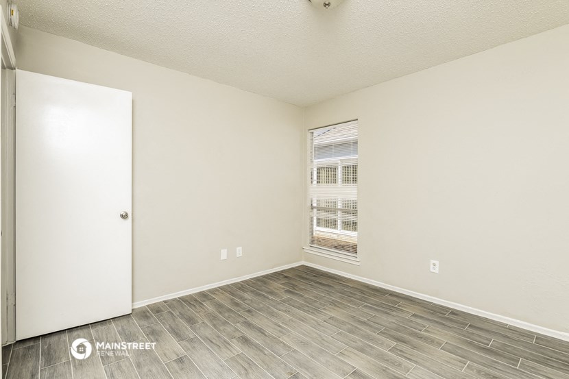 the spacious living room with wood flooring and a window