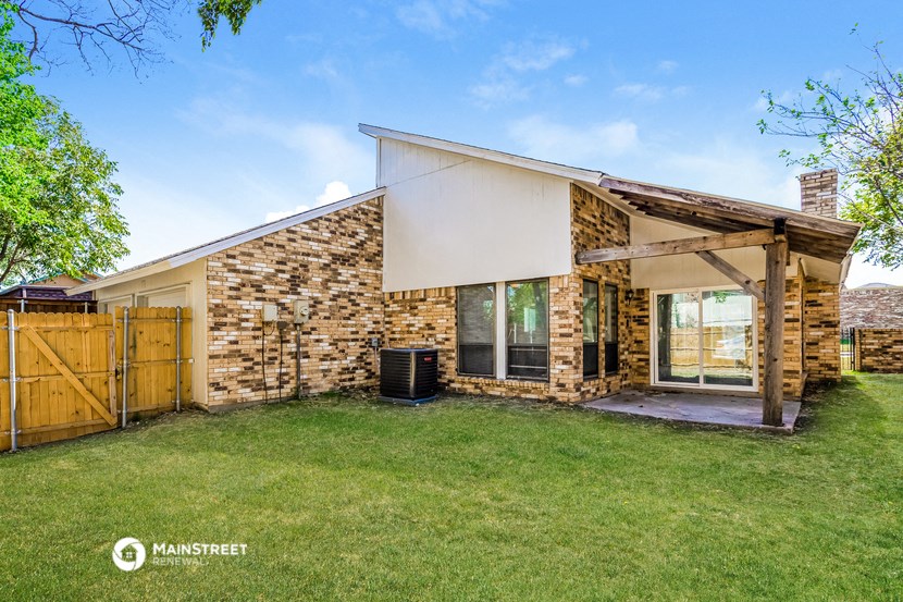 a small brick house with a yard and a wooden fence