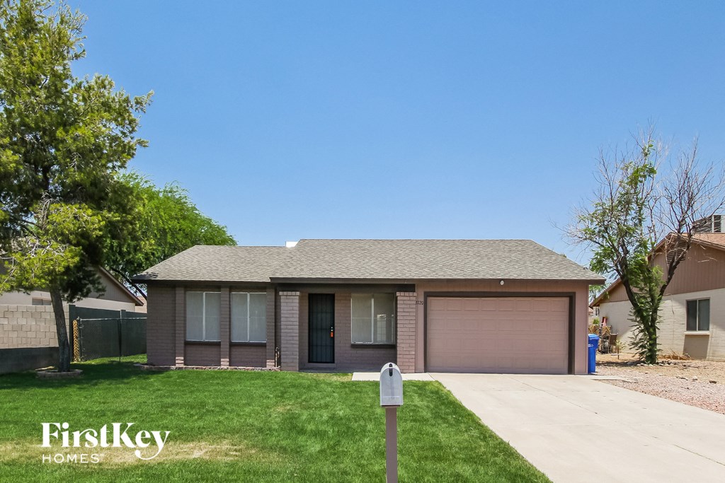 a small brown house with a driveway and lawn