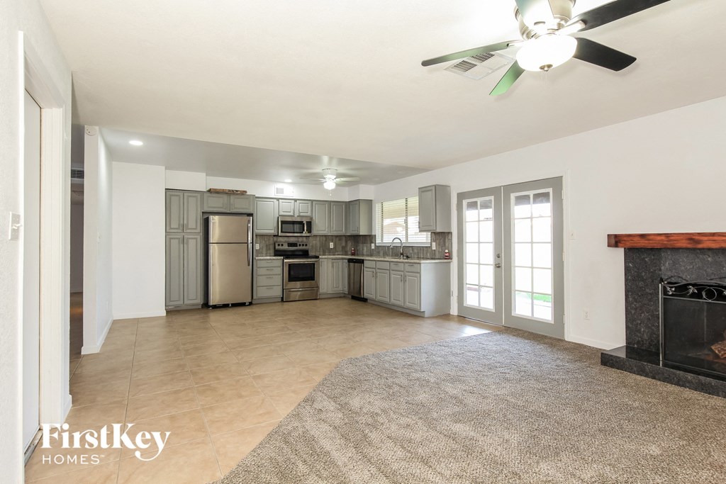 an empty living room with a fireplace and a kitchen