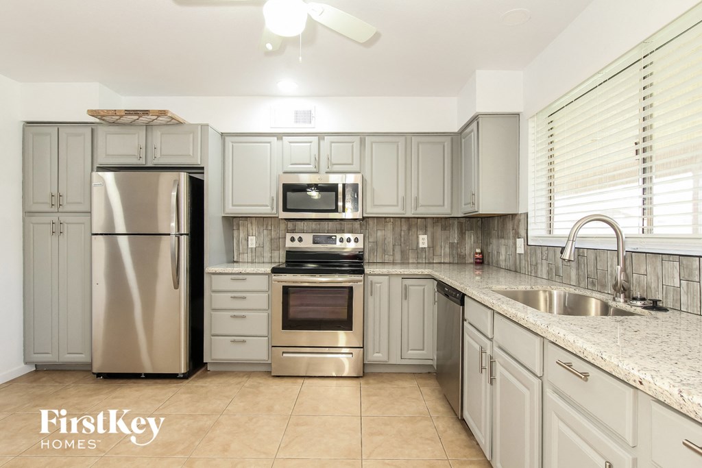 a white kitchen with stainless steel appliances and granite counter tops