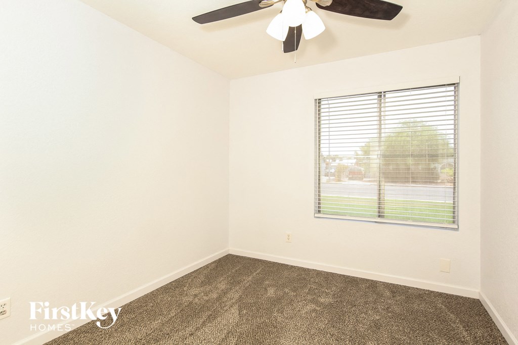 an empty room with a window and a ceiling fan